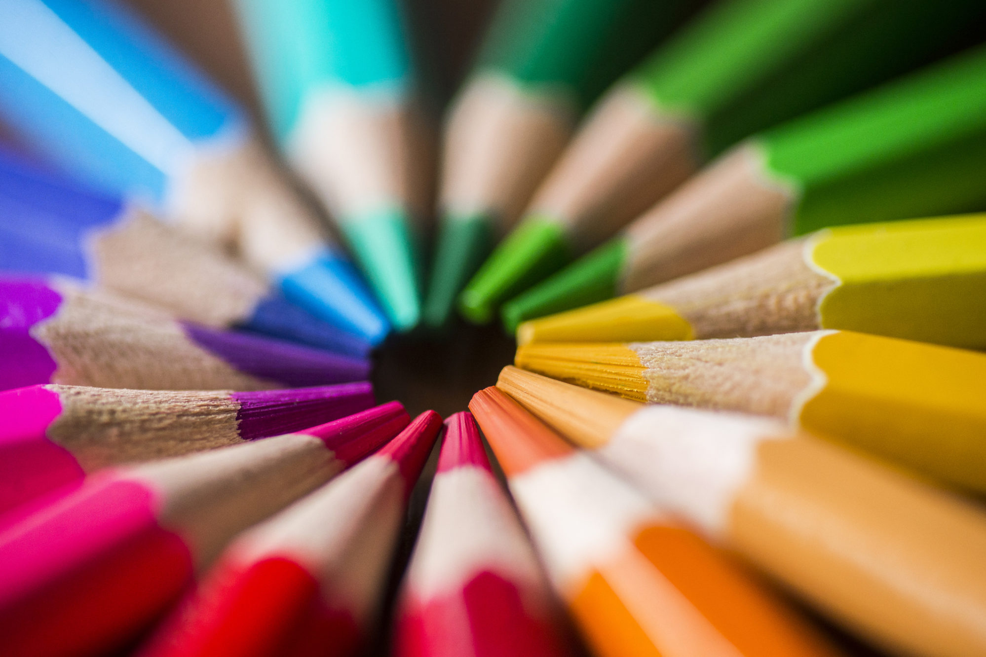 Buntstifte aus Holz und mit intensiven Farben. Die Spitzen zeigen alle in die Mitte und die Stifte bilden einen Kreis