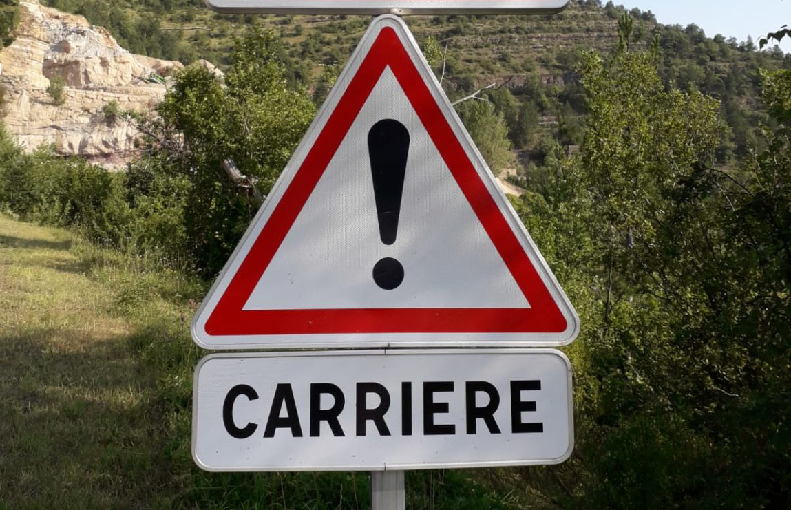 Ein Straßenschild mit Achtung-Warnzeichen und dem Wort "Carriere".